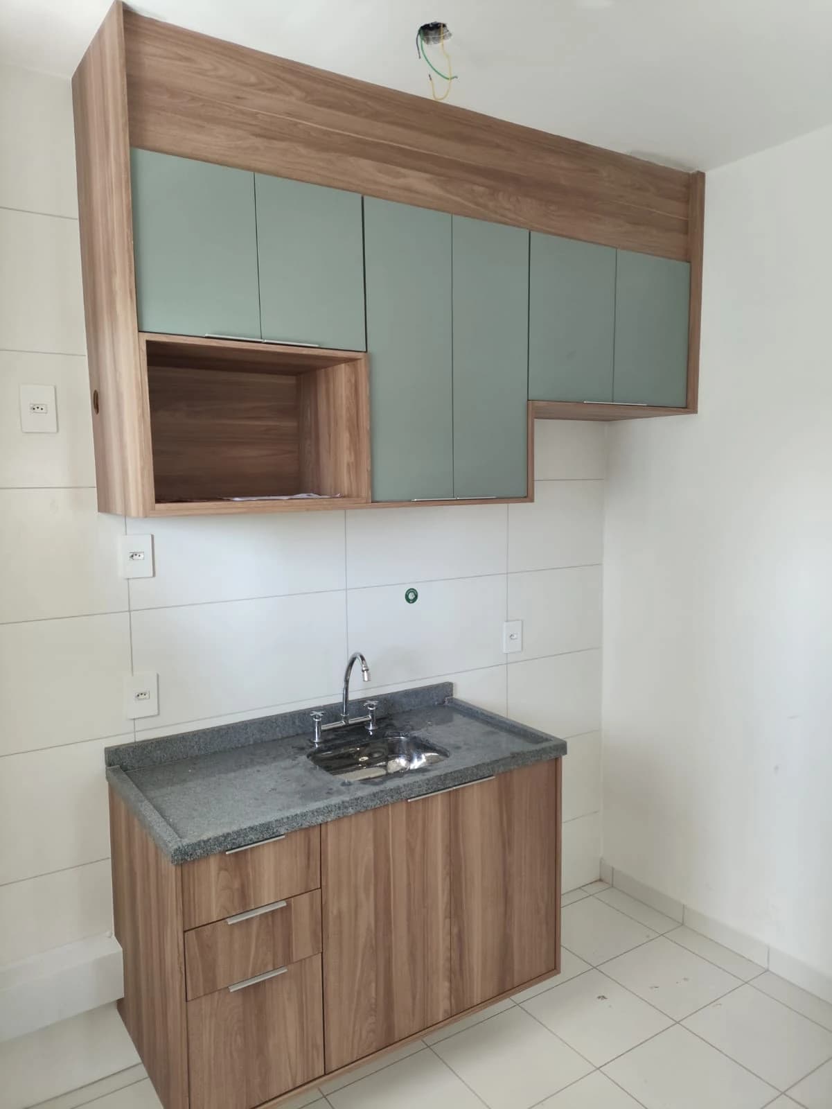 Cozinha Moderna com Armários: Ambiente contemporâneo com armários de madeira clara e portas verdes. A bancada em granito oferece funcionalidade, enquanto o design clean maximiza o espaço.