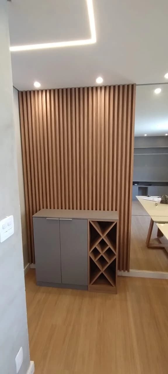Ambiente Moderno com Painel de Madeira: Espaço contemporâneo com design funcional. Painel de madeira em tons quentes, móveis em cinza e iluminação embutida destacam a elegância.